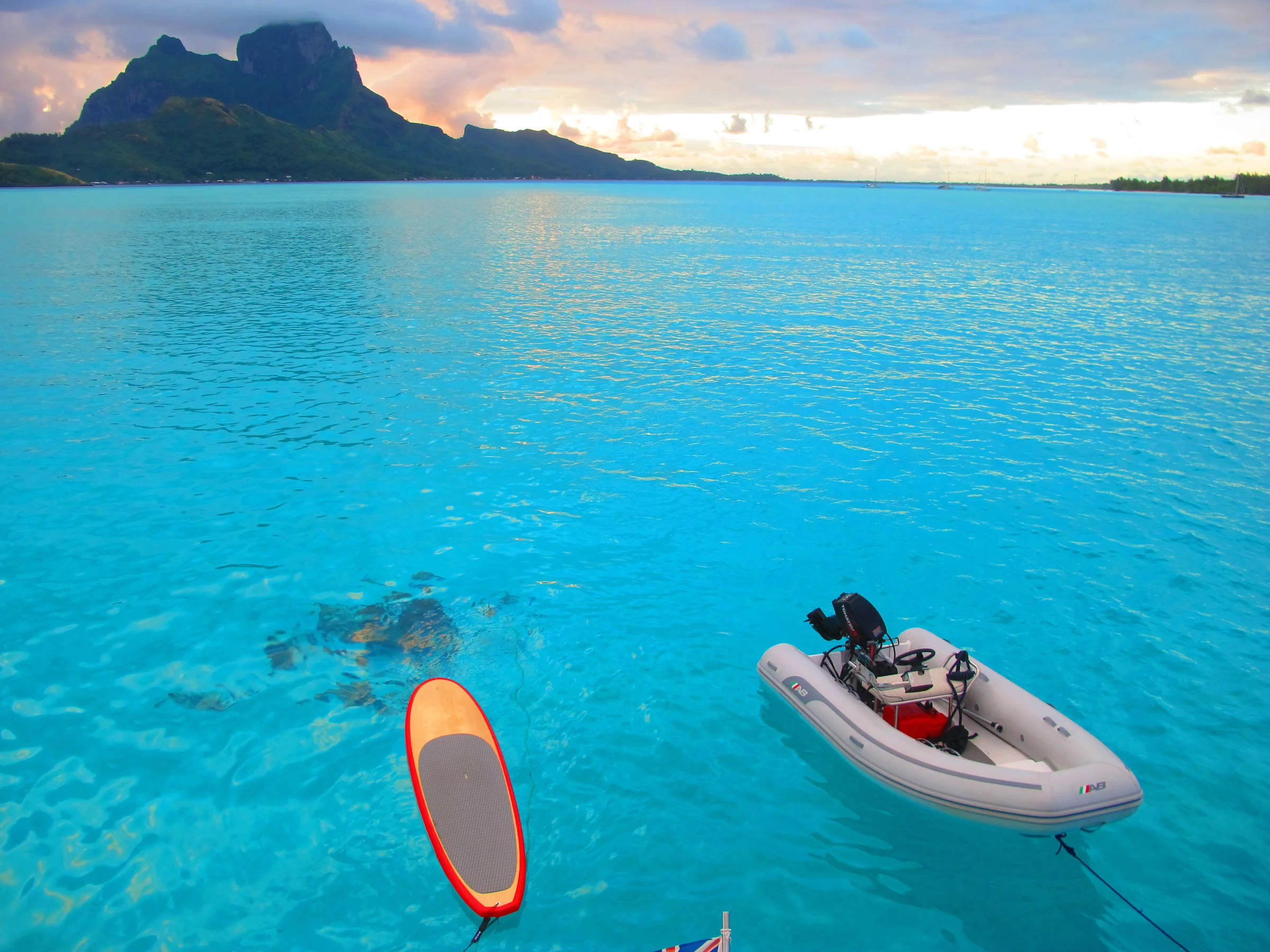 A yacht at anchor in Bora Bora with a tender and kayak alongside.